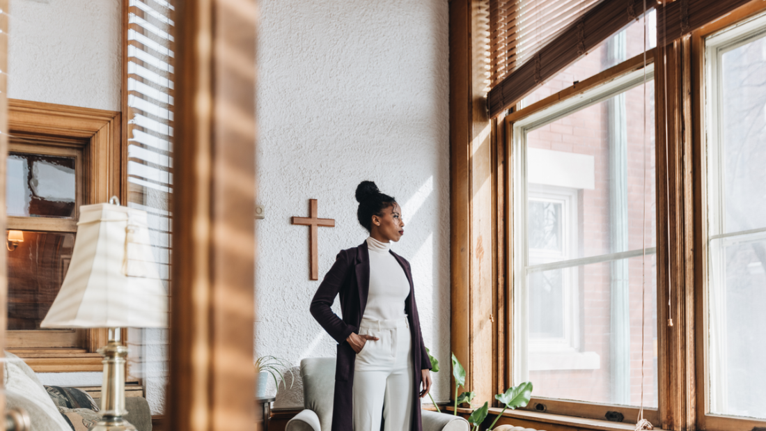 student standing next to a cross on a wall and looking out of a window